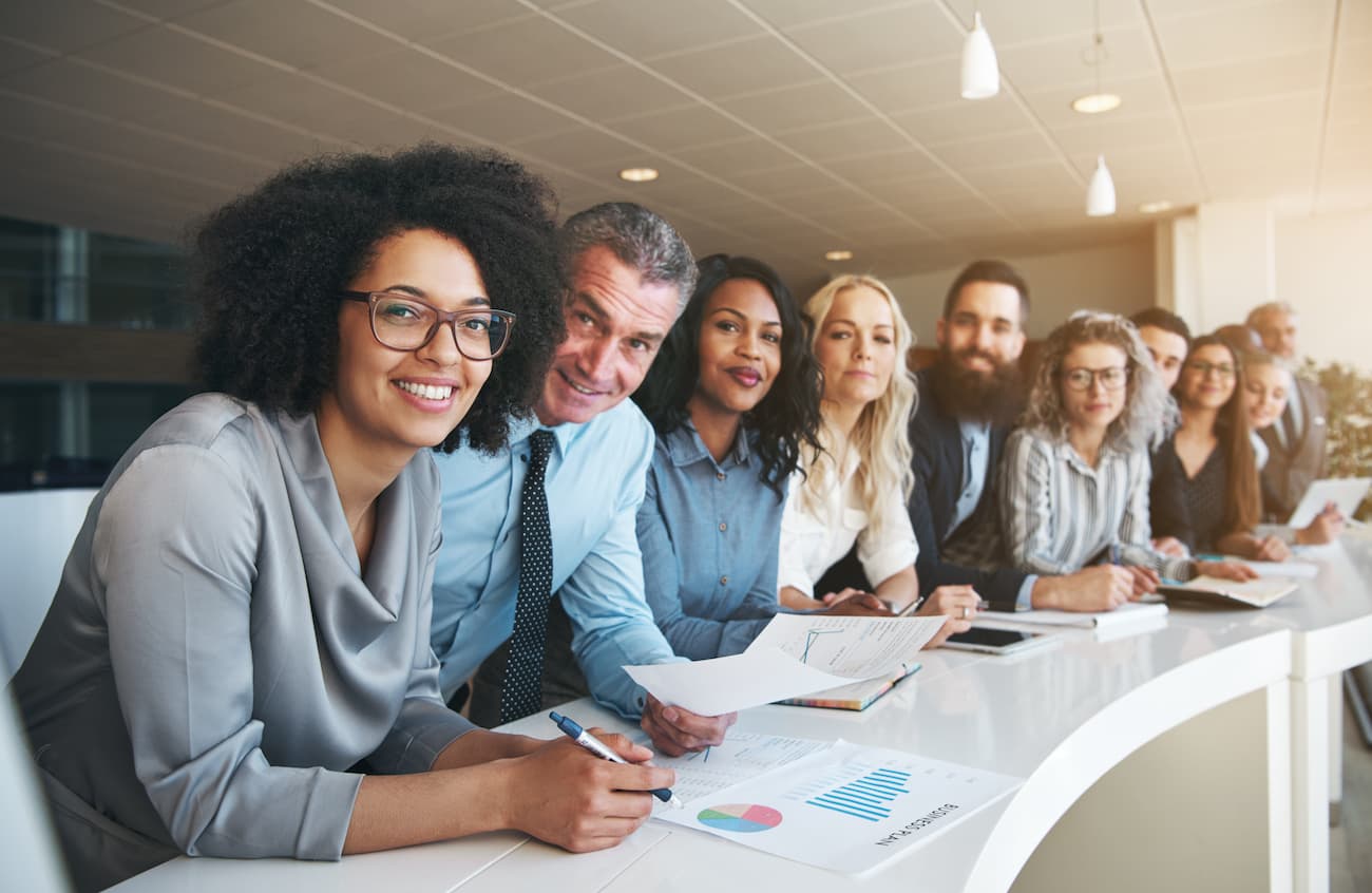 Vielfältiges und fröhliches Team von Fachkräften in einem modernen Büro, symbolisiert die Möglichkeit, durch Teilnahme an passbrains Tests, Umfragen und Studien mit flexiblem Zeiteinsatz gutes Geld zu verdienen.