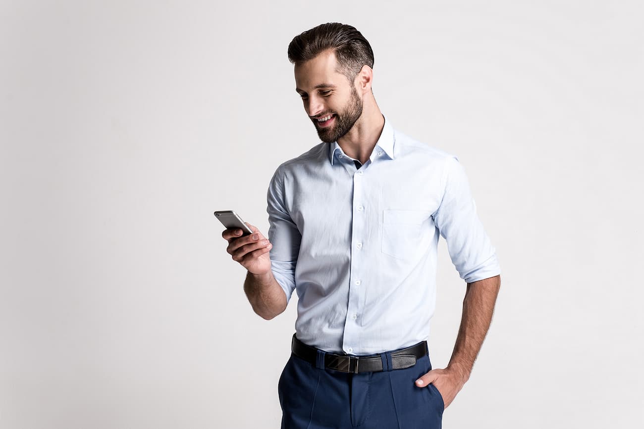 Ein junger Mann schaut auf sein Smartphone und lächelt, symbolisiert die einfache und schnelle Bereitstellung von strukturierten Berichten mit klaren Handlungsempfehlungen.