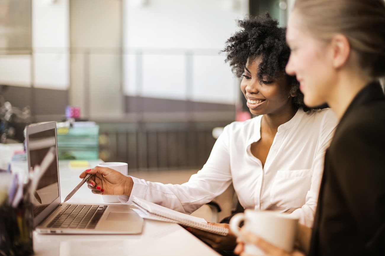 Zwei Frauen arbeiten gemeinsam an einem Laptop, symbolisieren Zeitersparnis durch schnelle Ergebnisse und Handlungsempfehlungen.